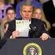 Bush holds up a Dayton, OH, fourth-grader's gold-star-adorned book report on Ferdinand Magellan.